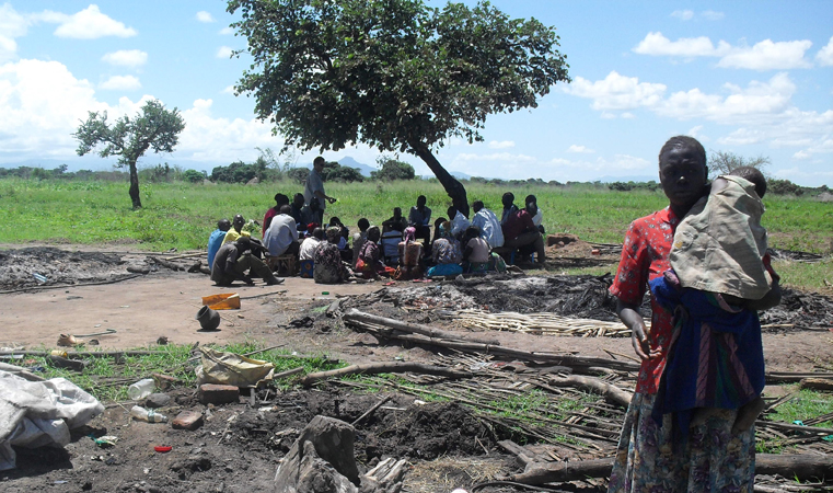 Grace Arach helplessly looks at what is left of her hut, as other families plot their next move under a tree