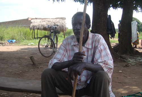 Mzee Ouma sits under a mango tree with his walking stick pondering his next move