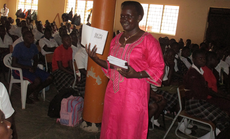 Gulu RDC cathrine Lamwaka displays the book to Graceland Girls