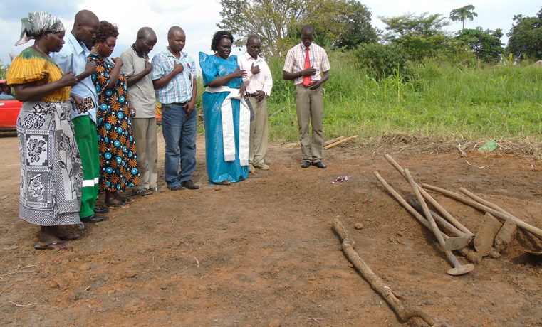 Gulu Woman MP Betty Aol Ocan praying accompanied by security officials and relatives offer prayers on Sabina Adong’s grave at Ito Duny village, Koro Sub County, in Gulu district