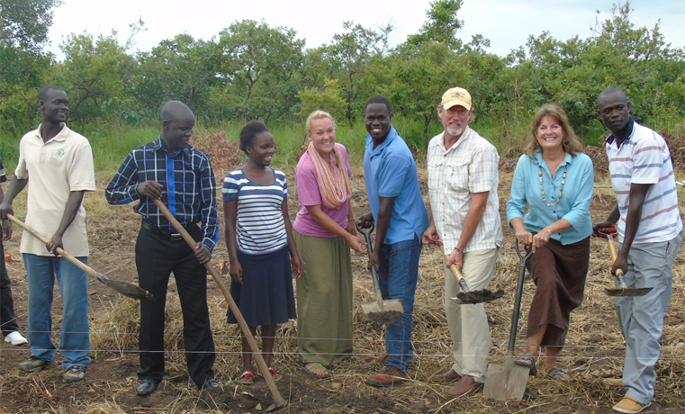 American couple, David (wearing cap) and his wife Dana Mann (with necklace) and Gulu LCV Chairman Martin Ojara Mapenduzi (wearing blue strip shirt) dig a foundation for Olee Community Primary School in Paicho Sub County on Wednesday.