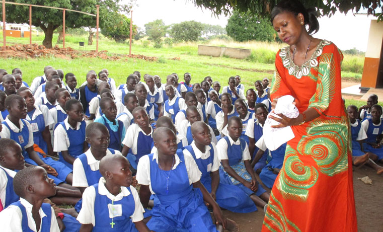 Caroline Bonabano the principal legal officer demonstrate to pupils of Awach P7 how to use sanitary pads