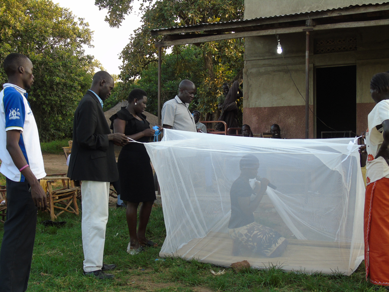 Douglas Peter Okello, the District Council Speaker (extreme left), demonstrating with health workers how set up Mosquito Net to communities in of Ajuri, Lalogi Sub County in Gulu district on Saturday