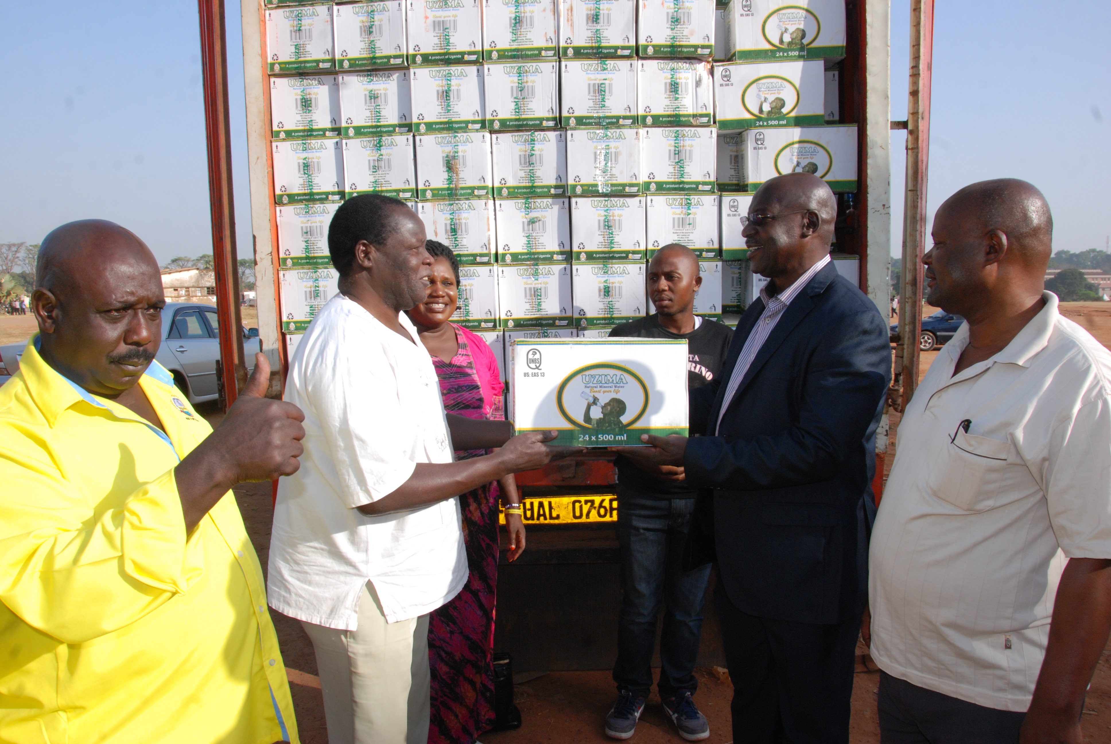 General Oketta handing over a box of water to Capt Santo Okot Lapolo Gulu RDC as townclerk looks on at the far right