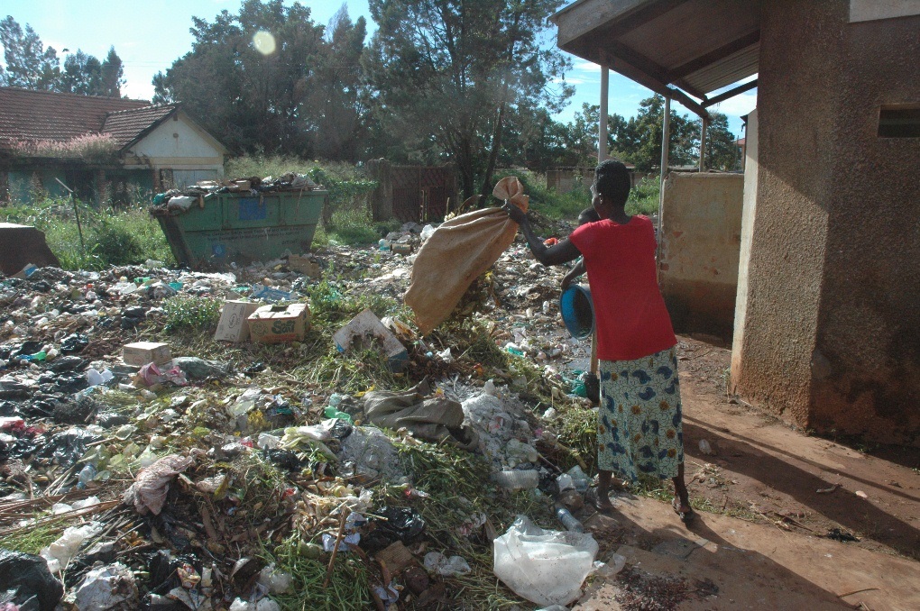 A woman dumps garbage at the site close to Wilobo market in Gulu recently . PHOTO BY TERENCE ALUR. (1)