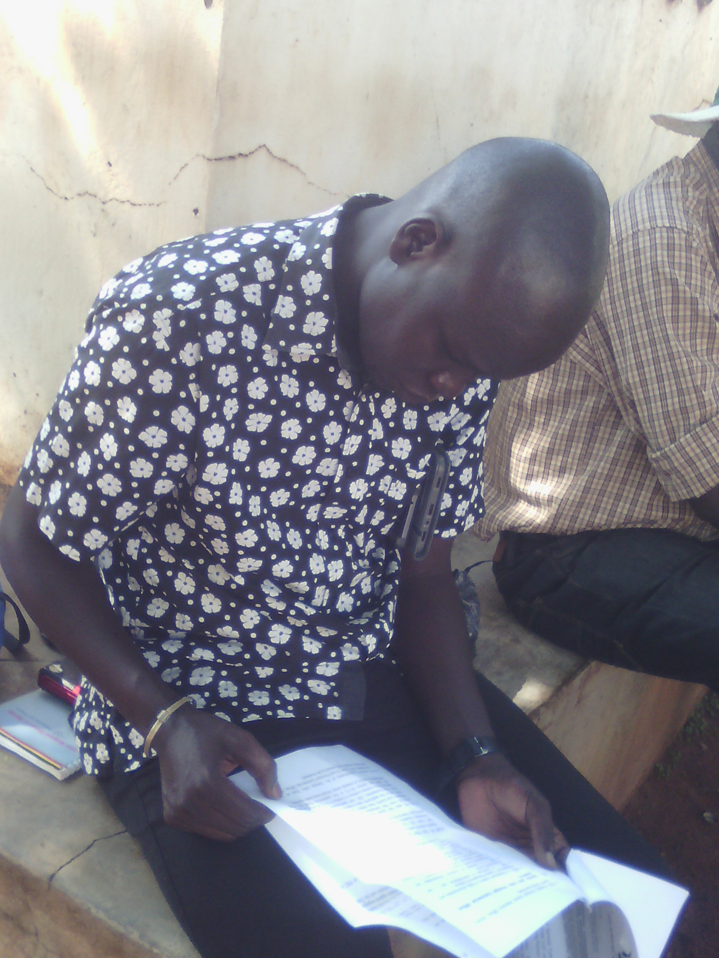 Gulu district Chairman Ojara Martin Mapeenduzi reads through a copy of the Letter from the Public Service commision