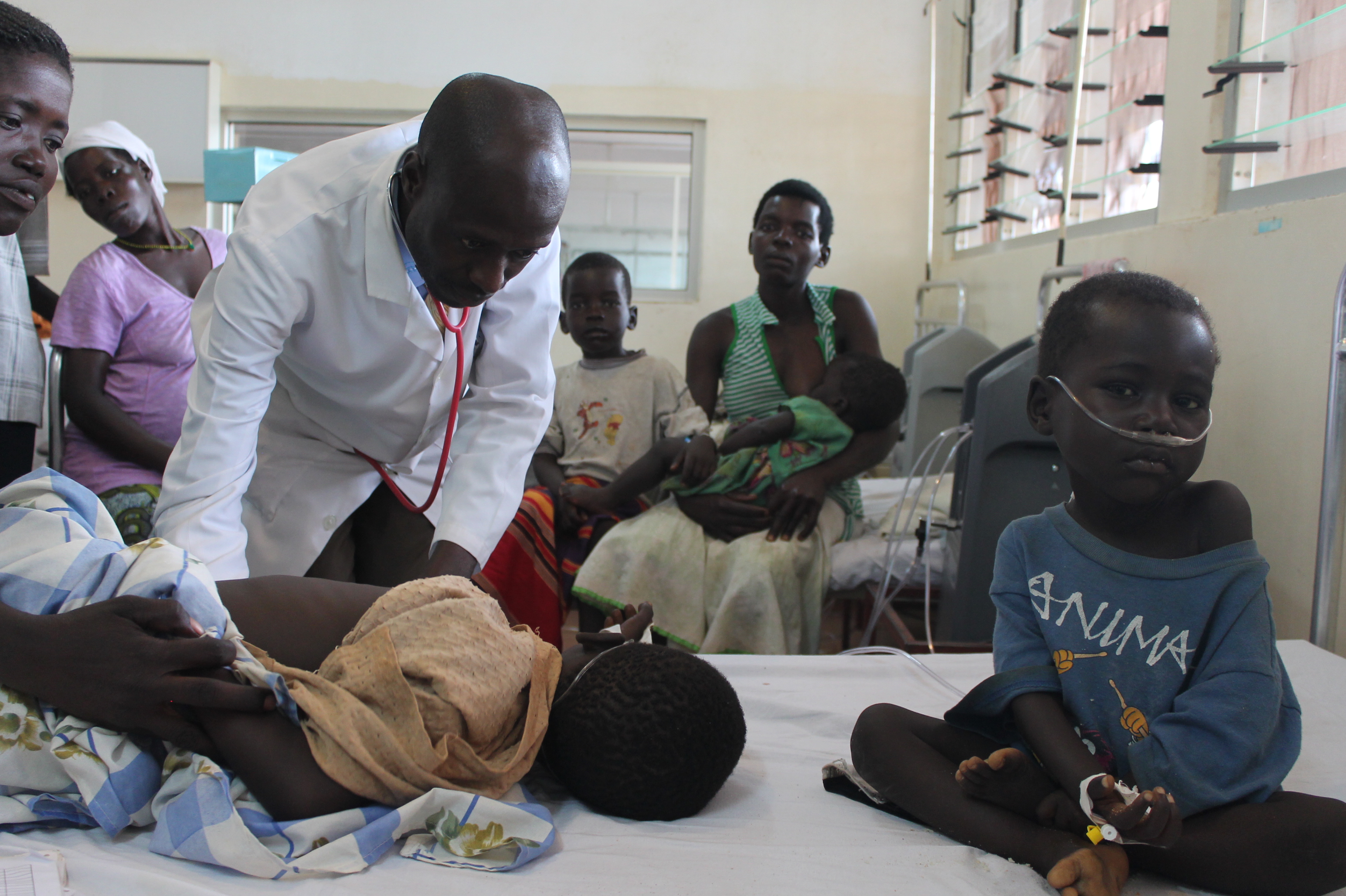 Doctor Nyeko examines a child sharing bed with another child at the ICU ward